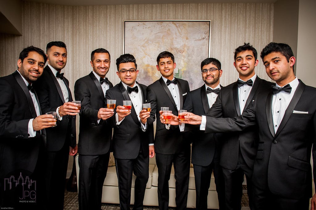 Groom and groomsmen in black tie formal wear at Chas Baker wedding fitting